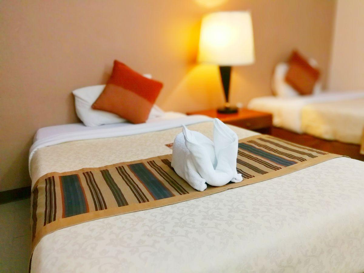 Close-up of fresh white bath towels on the bed sheet. Room service maid cleaning hotel room. 