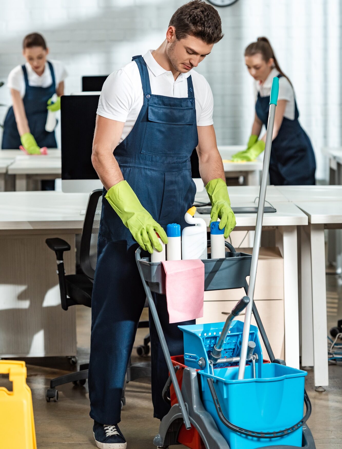 young cleaner standing near cart with cleaning supplies